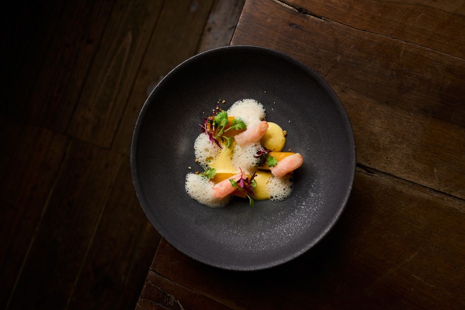 Cultura São Paulo — Elegant seafood dish with foam, herbs, and microgreens on a black plate.